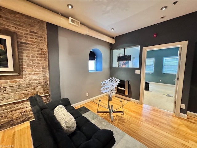 220 Market St Unit 110, Greensboro, NC 27401 - living room with light wood finished floors, baseboards, recessed lighting, and brick wall