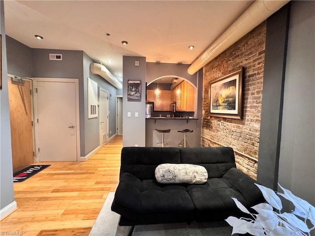 220 Market St Unit 110, Greensboro, NC 27401 - living area featuring light wood-type flooring, arched walkways, brick wall, baseboards, and recessed lighting
