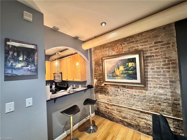 220 Market St Unit 110, Greensboro, NC 27401 - bar area with wood finished floors, electric stove, brick wall, and pendant lighting