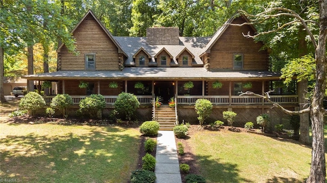 log home with covered porch and a front yard