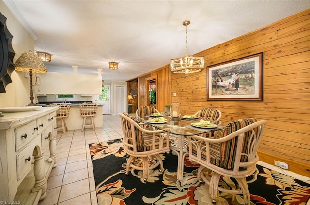 dining room featuring a chandelier, wood walls, and light tile floors