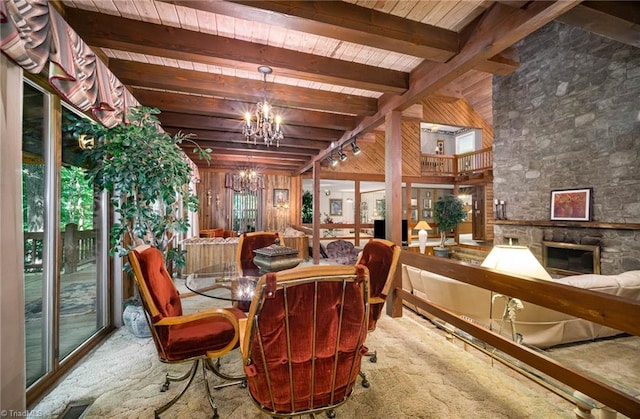 interior space with wooden ceiling, a stone fireplace, a notable chandelier, and beam ceiling