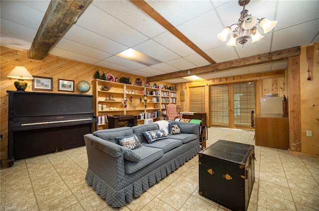 living room with light tile floors, a notable chandelier, beamed ceiling, a paneled ceiling, and wooden walls