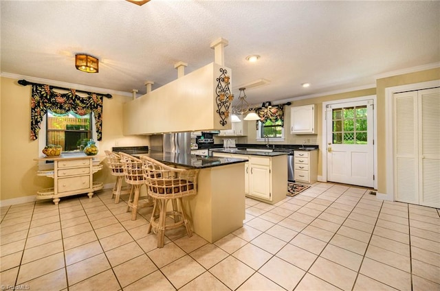 kitchen featuring decorative light fixtures, a breakfast bar, light tile floors, and white cabinetry