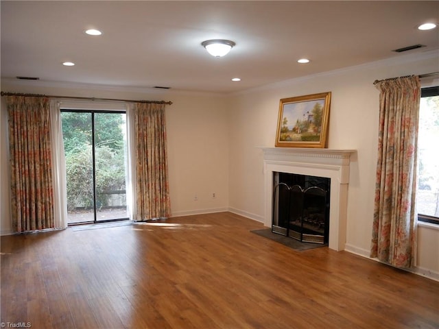 unfurnished living room with a healthy amount of sunlight, wood-type flooring, and ornamental molding