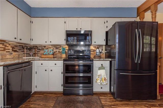 kitchen featuring dark wood-type flooring, stone counters, decorative backsplash, appliances with stainless steel finishes, and white cabinetry