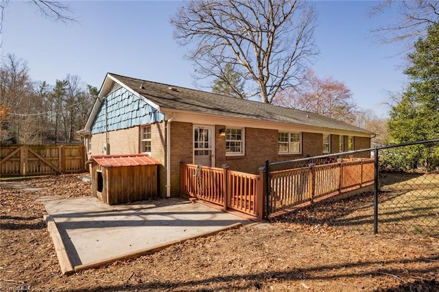 back of house with brick siding, a patio, and fence