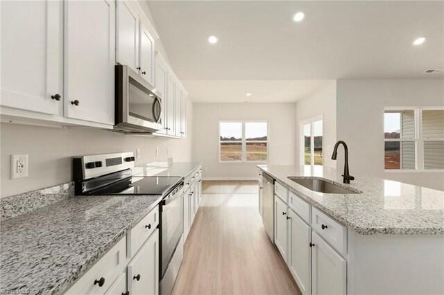 kitchen featuring white cabinets, recessed lighting, a center island with sink, appliances with stainless steel finishes, and a sink