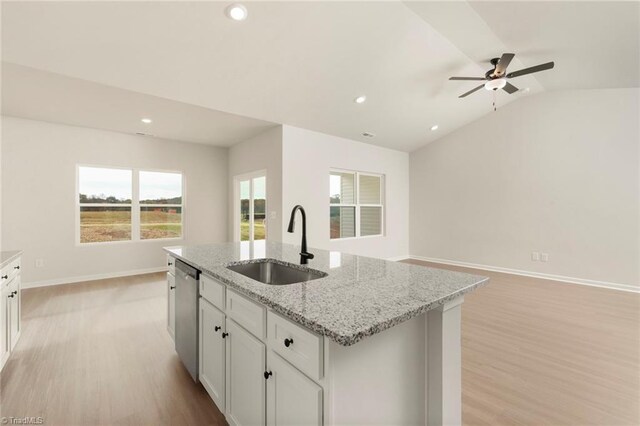 kitchen with dishwasher, an island with sink, a sink, light wood-style floors, and vaulted ceiling
