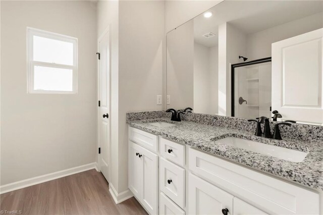 bathroom with baseboards, a sink, a stall shower, and wood finished floors
