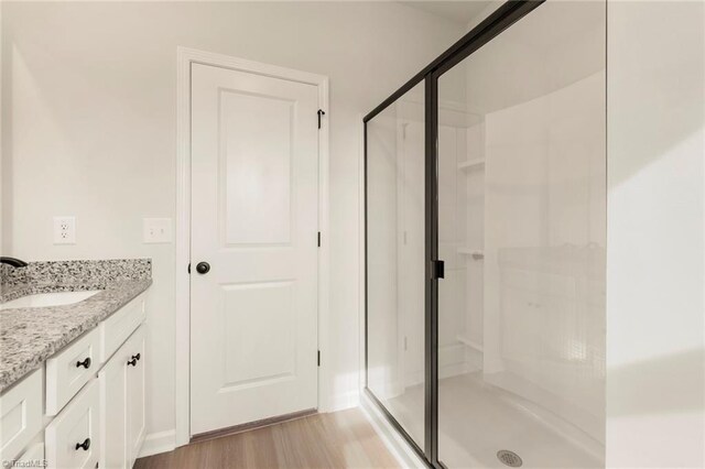 full bathroom with a stall shower, wood finished floors, and vanity