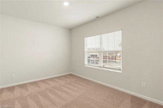 empty room with baseboards, visible vents, and light colored carpet