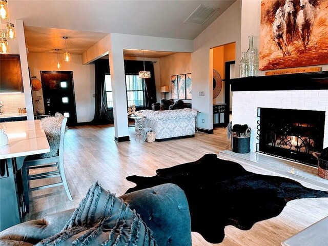 kitchen featuring stainless steel appliances, light wood-type flooring, sink, decorative light fixtures, and wall chimney exhaust hood