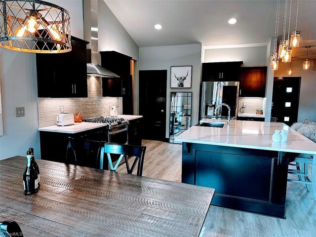 kitchen with tasteful backsplash, appliances with stainless steel finishes, a large island, light hardwood / wood-style floors, and decorative light fixtures