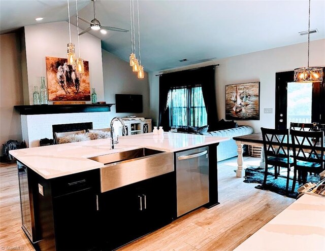 kitchen with lofted ceiling, a fireplace, a center island with sink, light wood-type flooring, and stainless steel appliances