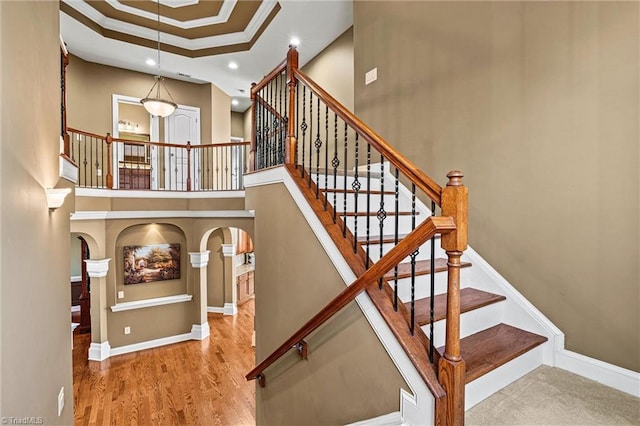 staircase with a towering ceiling, baseboards, and ornamental molding