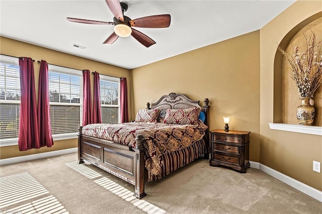 bedroom featuring baseboards, multiple windows, visible vents, and light colored carpet