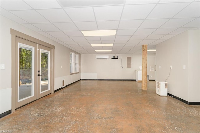 basement with electric panel, a wall mounted air conditioner, and a paneled ceiling