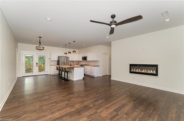 unfurnished living room featuring french doors, ceiling fan, sink, and dark hardwood / wood-style floors