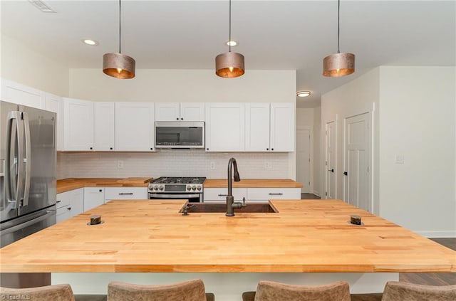 kitchen featuring white cabinetry, stainless steel appliances, sink, and pendant lighting