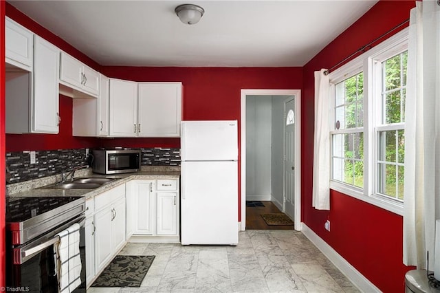 1519 Graves Ave, High Point, NC 27260 - kitchen with stainless steel appliances, a sink, baseboards, white cabinetry, and backsplash