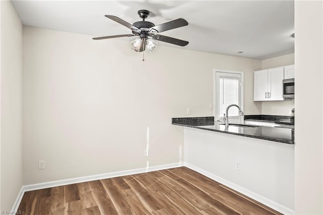 kitchen with white cabinetry, sink, dark stone counters, dark wood-type flooring, and appliances with stainless steel finishes