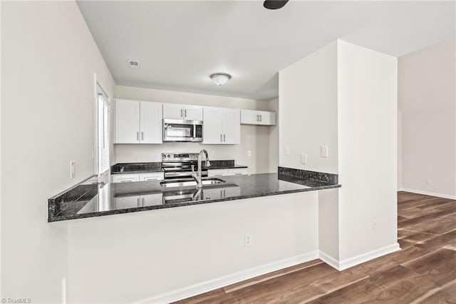 kitchen featuring white cabinets, kitchen peninsula, stainless steel appliances, and sink