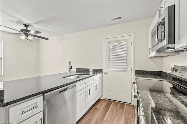 kitchen featuring white cabinetry, sink, dark stone counters, appliances with stainless steel finishes, and hardwood / wood-style floors