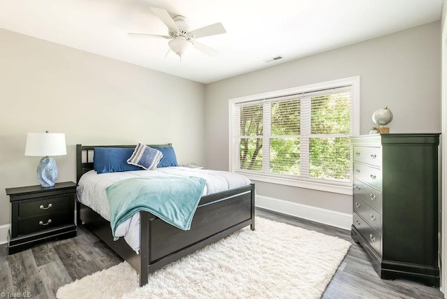 bedroom featuring baseboards, a ceiling fan, wood finished floors, and visible vents