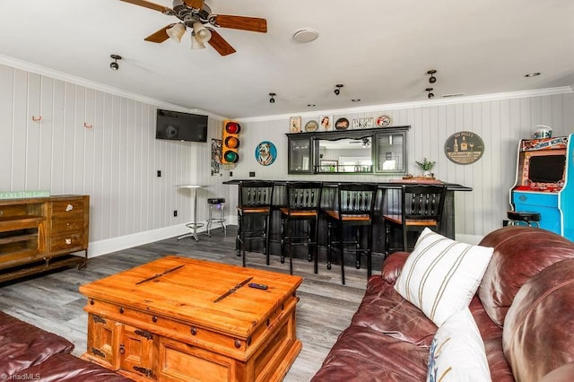 living area with ornamental molding, a ceiling fan, and wood finished floors