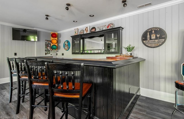 bar featuring wet bar, visible vents, wood finished floors, baseboards, and ornamental molding