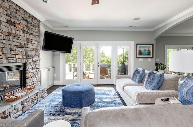 living area featuring french doors, arched walkways, a fireplace, and ornamental molding