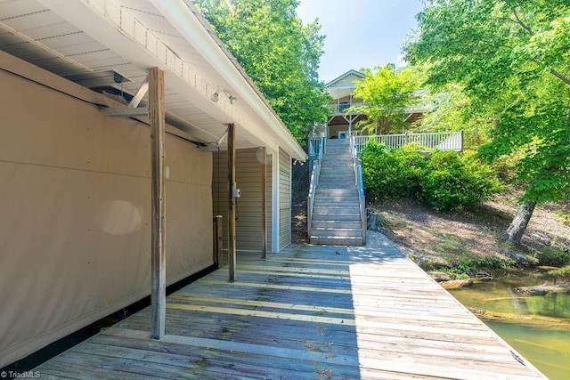 exterior space featuring a deck with water view and stairway