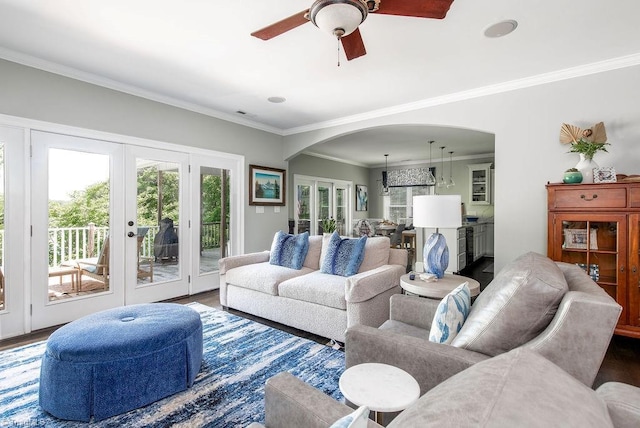 living area with crown molding, arched walkways, french doors, a ceiling fan, and wood finished floors