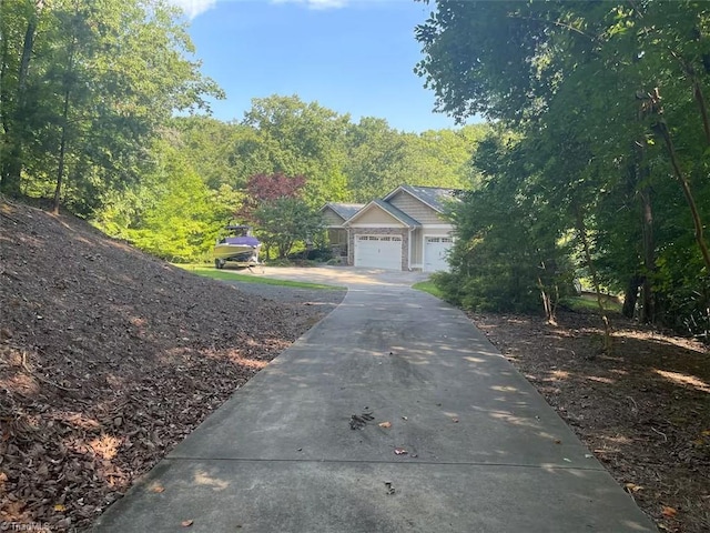 exterior space featuring an attached garage, concrete driveway, and a forest view