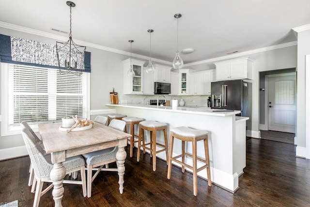 kitchen with black microwave, an inviting chandelier, a peninsula, dark wood-style floors, and glass insert cabinets
