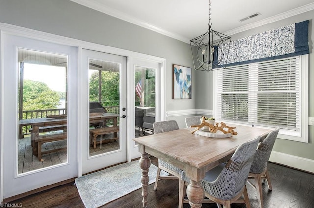 dining area featuring visible vents, dark wood-type flooring, crown molding, and a notable chandelier