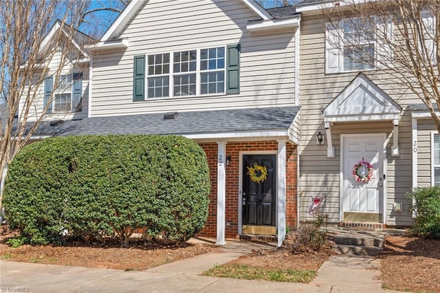 view of front of house with a shingled roof and brick siding