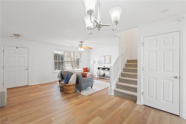 entryway with light wood finished floors, stairs, baseboards, and ceiling fan with notable chandelier