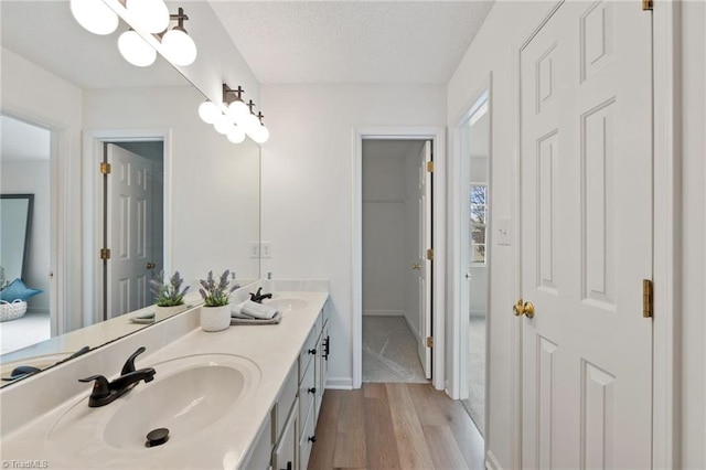 bathroom featuring double vanity, a sink, a textured ceiling, and wood finished floors