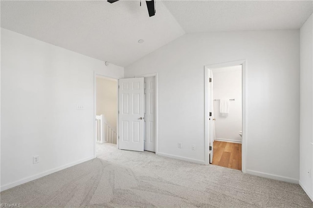 unfurnished bedroom featuring lofted ceiling, carpet flooring, baseboards, and ensuite bathroom