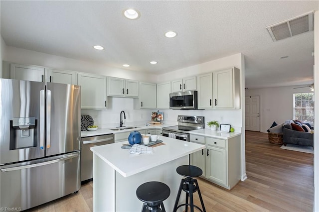 kitchen featuring visible vents, a kitchen breakfast bar, stainless steel appliances, light countertops, and a sink