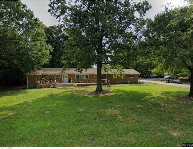 ranch-style house featuring a front yard and a wooden deck