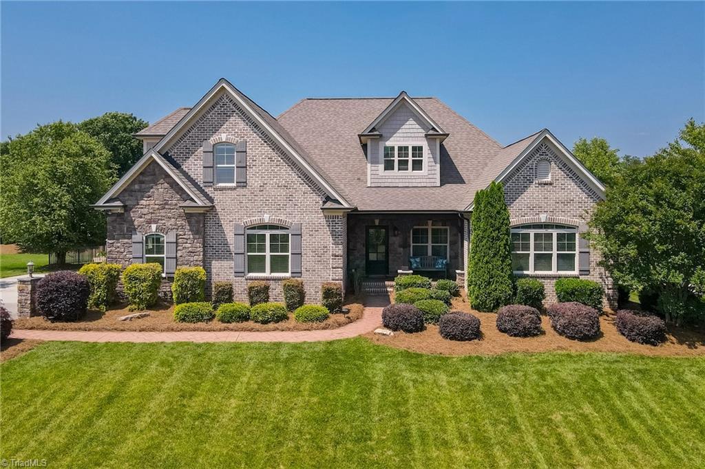3309 Serenity Ridge Ln, Tobaccoville, NC 27050 - view of front of property featuring a front yard, a porch, brick siding, and roof with shingles