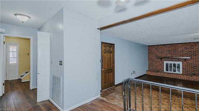 corridor with a textured ceiling and dark hardwood / wood-style flooring