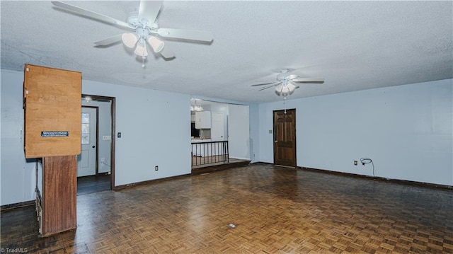 empty room with ceiling fan, a textured ceiling, and dark parquet floors