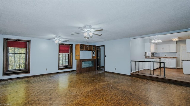 unfurnished living room featuring ceiling fan with notable chandelier, sink, a textured ceiling, and dark parquet floors