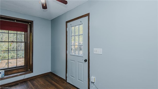 doorway to outside with ceiling fan, dark wood-type flooring, a textured ceiling, and plenty of natural light