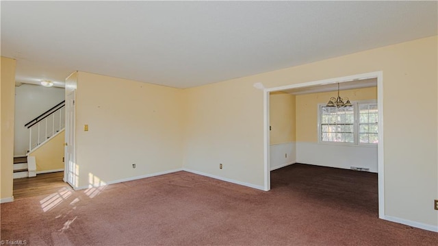 carpeted spare room featuring a chandelier