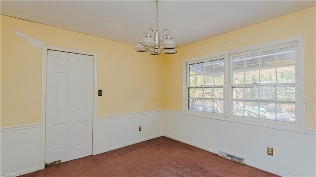 carpeted spare room with a chandelier